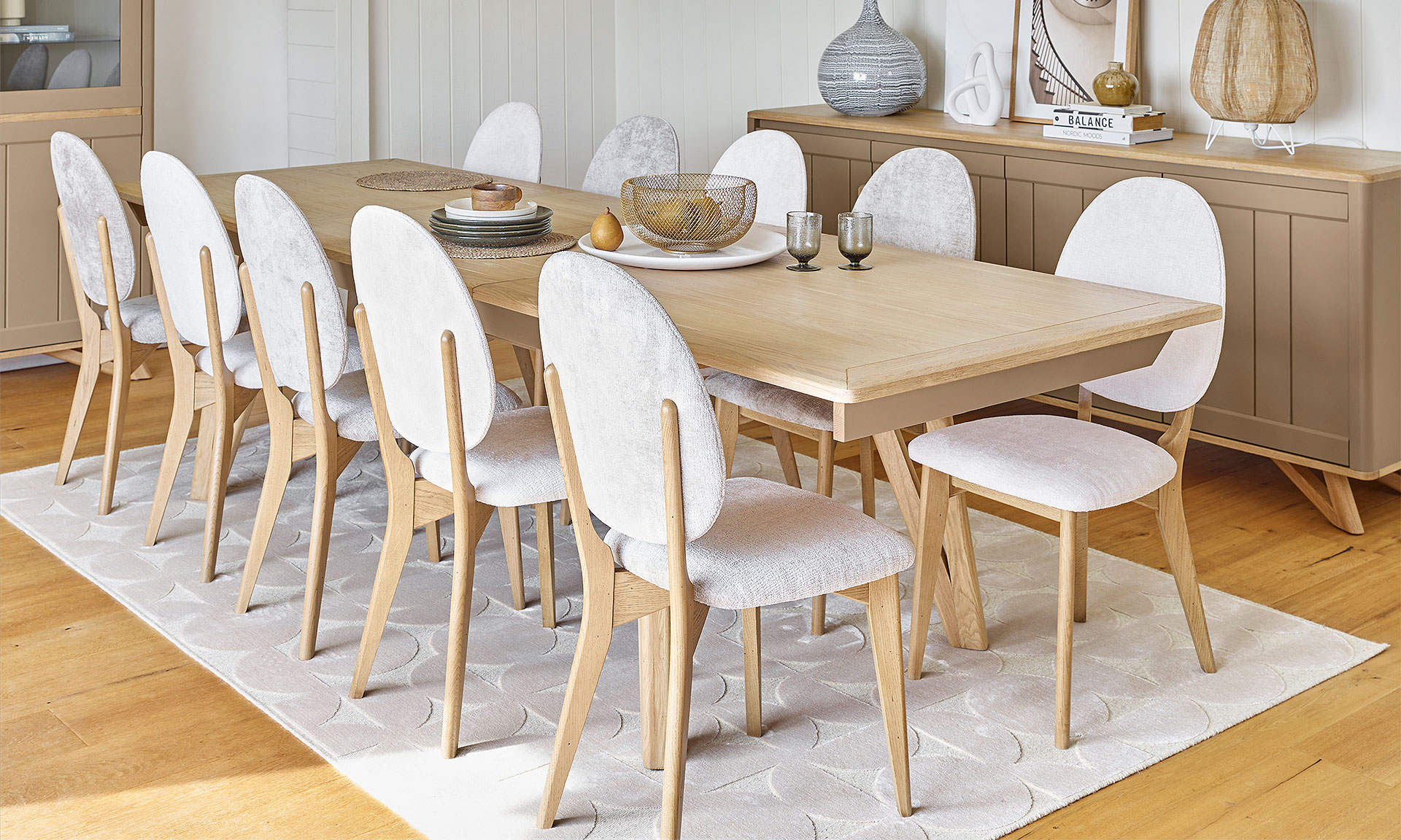 Photo d'une salle à manger avec une collection comportant une table de repas, une enfilade et des chaises. Les meubles présente des finitions chêne massif blond et peint en argile.